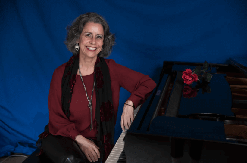 Schweizer konzertpianistin Marian Rosenfeld am Flügel vor blauem Hintergrund