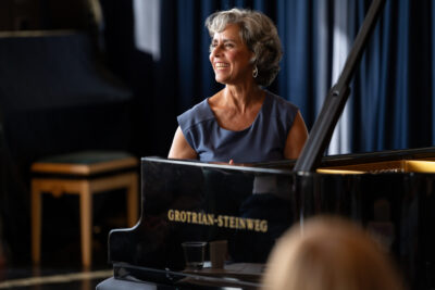 Marian Rosenfeld am Klavier, lachend dem Publikum zugewandt